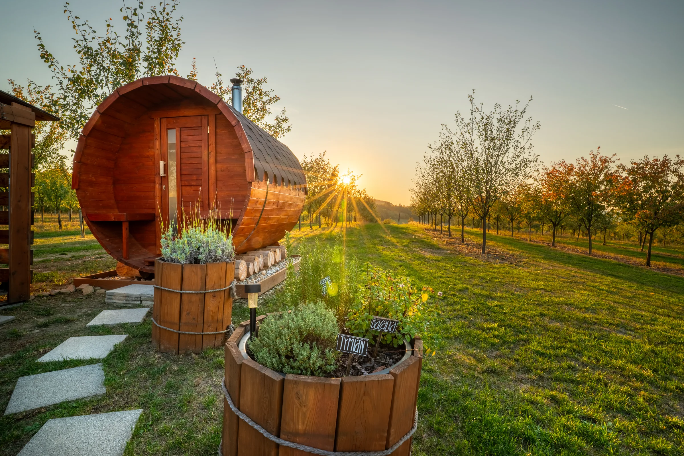 Tiny house Glampidol se saunou v trnkovém sadu při západu slunce